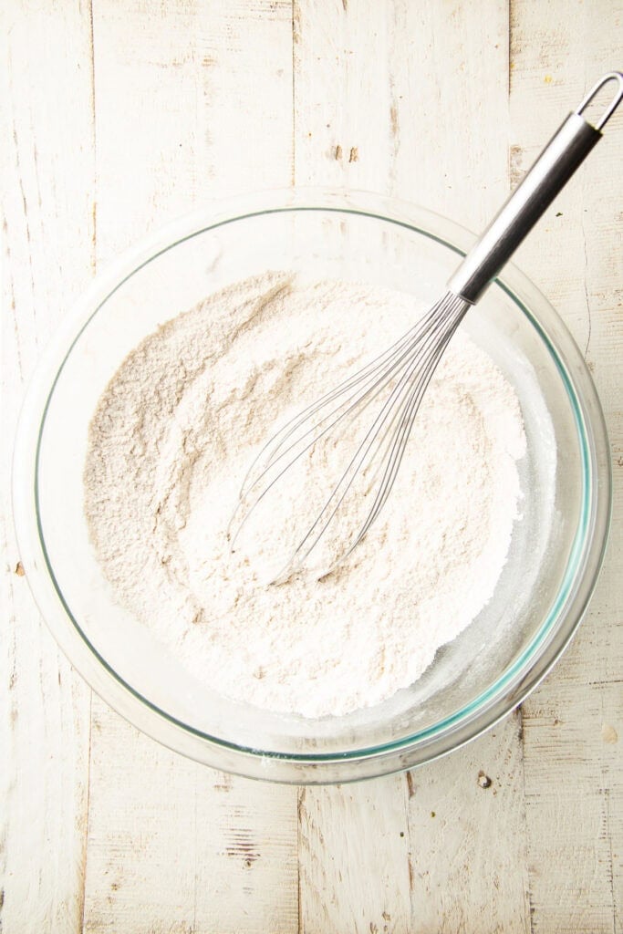 Dry ingredients for Apple Cider Doughnut Cake in a mixing bowl with whisk.