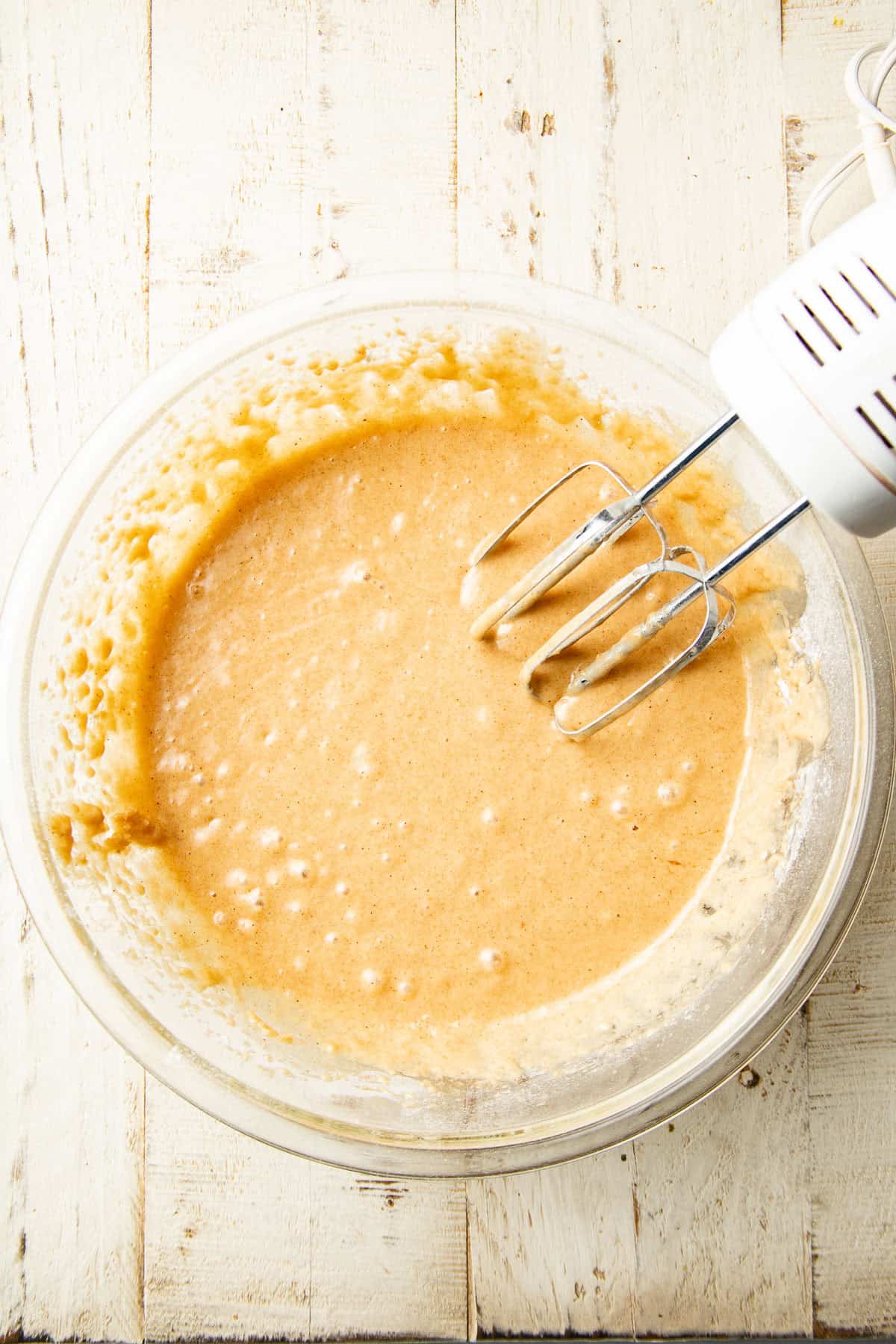 Cake batter in a mixing bowl with electric mixer.