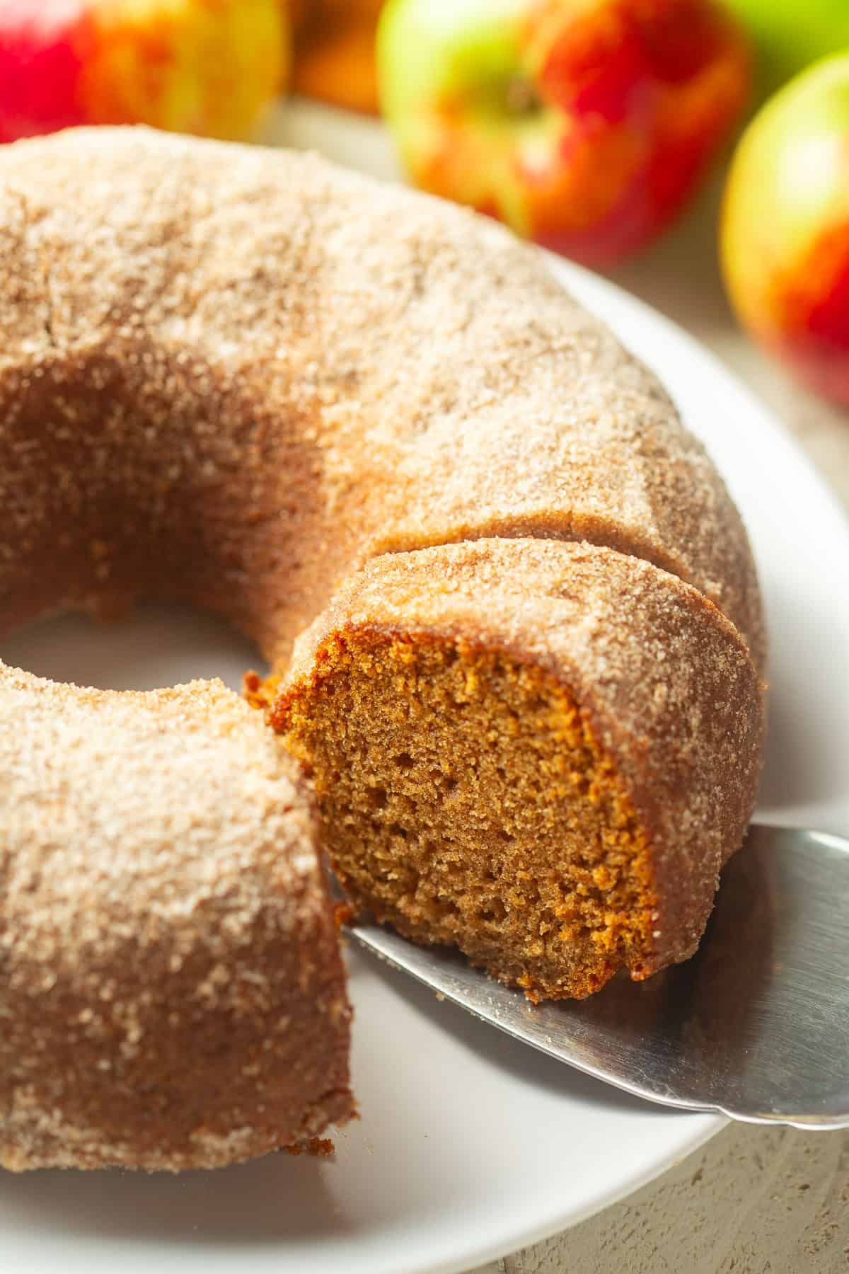Cake server lifting a slice of Apple Cider Doughnut Cake.