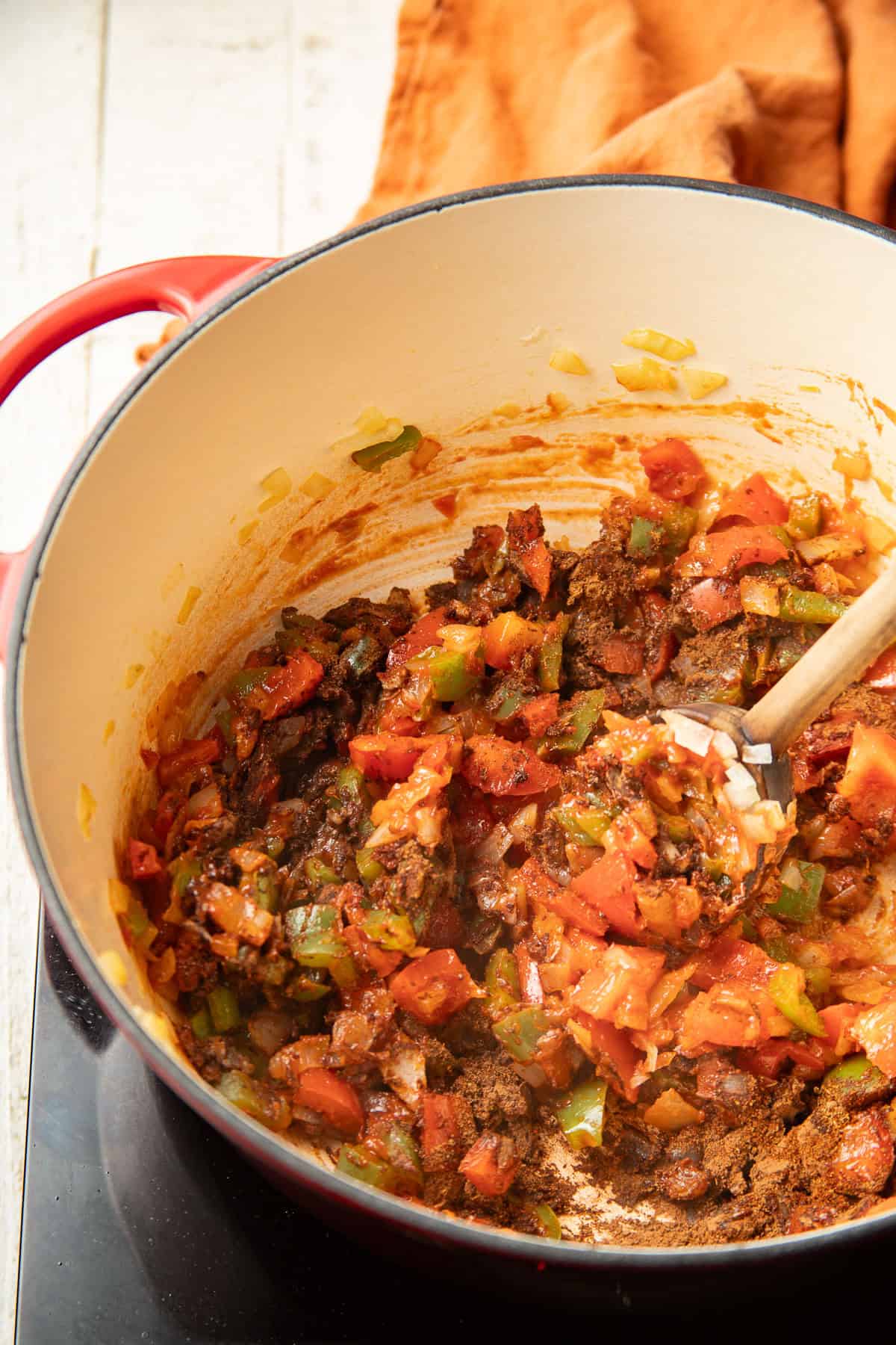 Diced peppers and onions cooking in pot with spices and tomato paste.