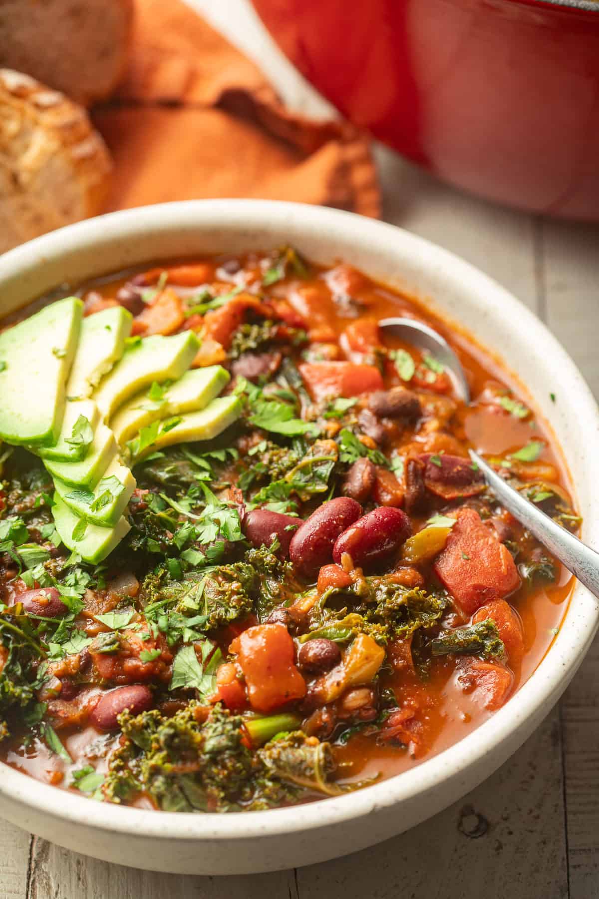 Bowl of Kale Chili topped with sliced avocado.