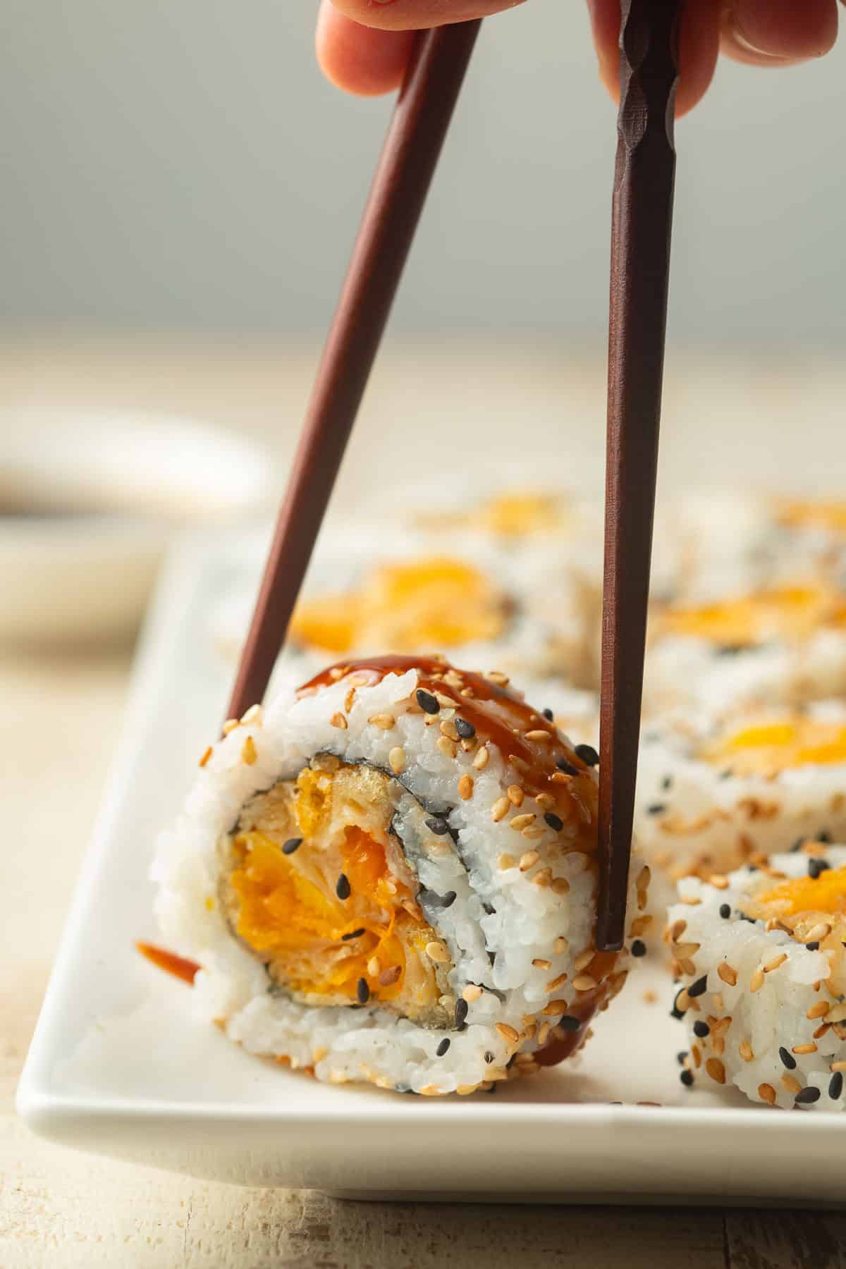 Chopsticks picking up a piece of Pumpkin Sushi.