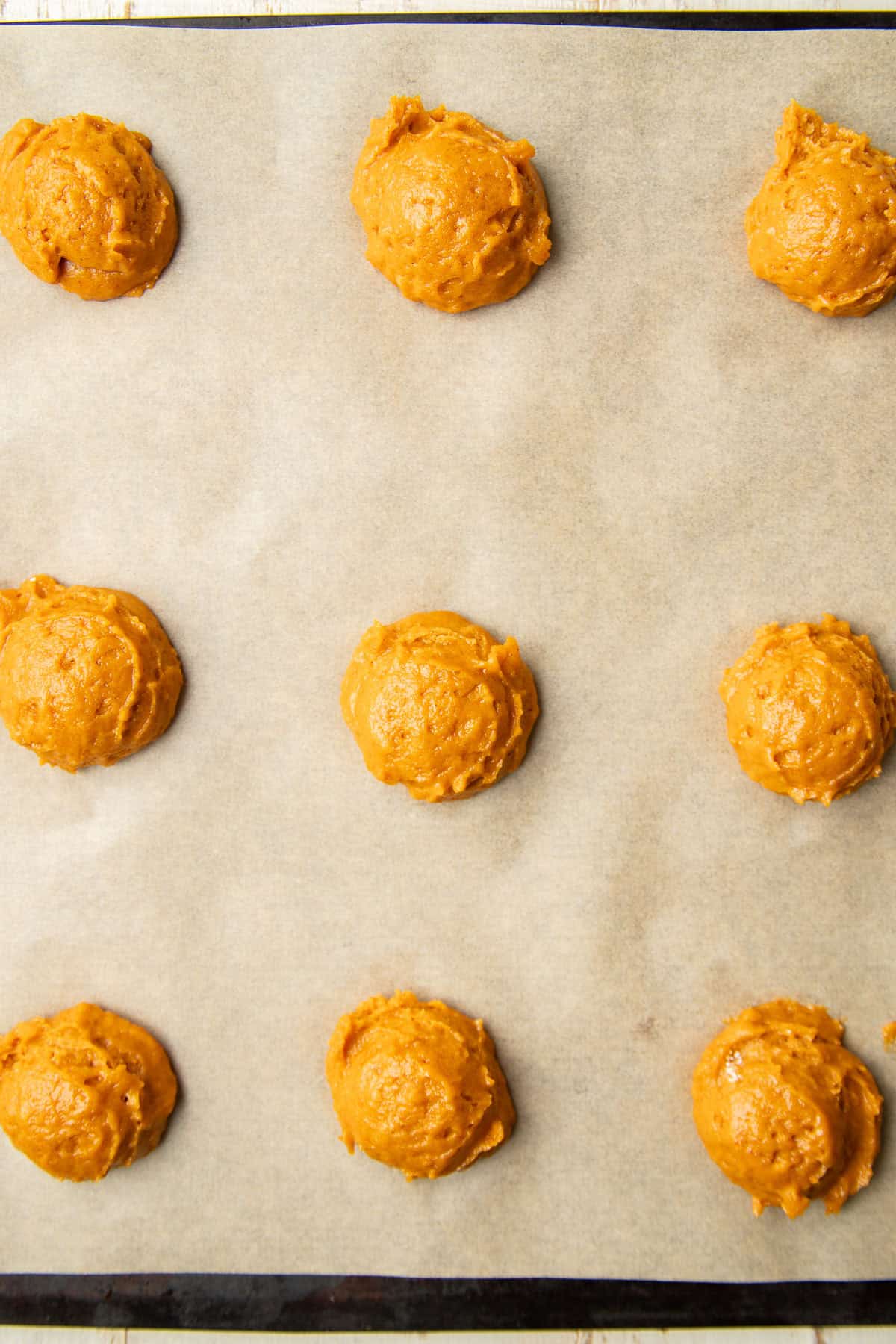 Unbaked Vegan Pumpkin Whoopie Pie halves on a baking sheet.