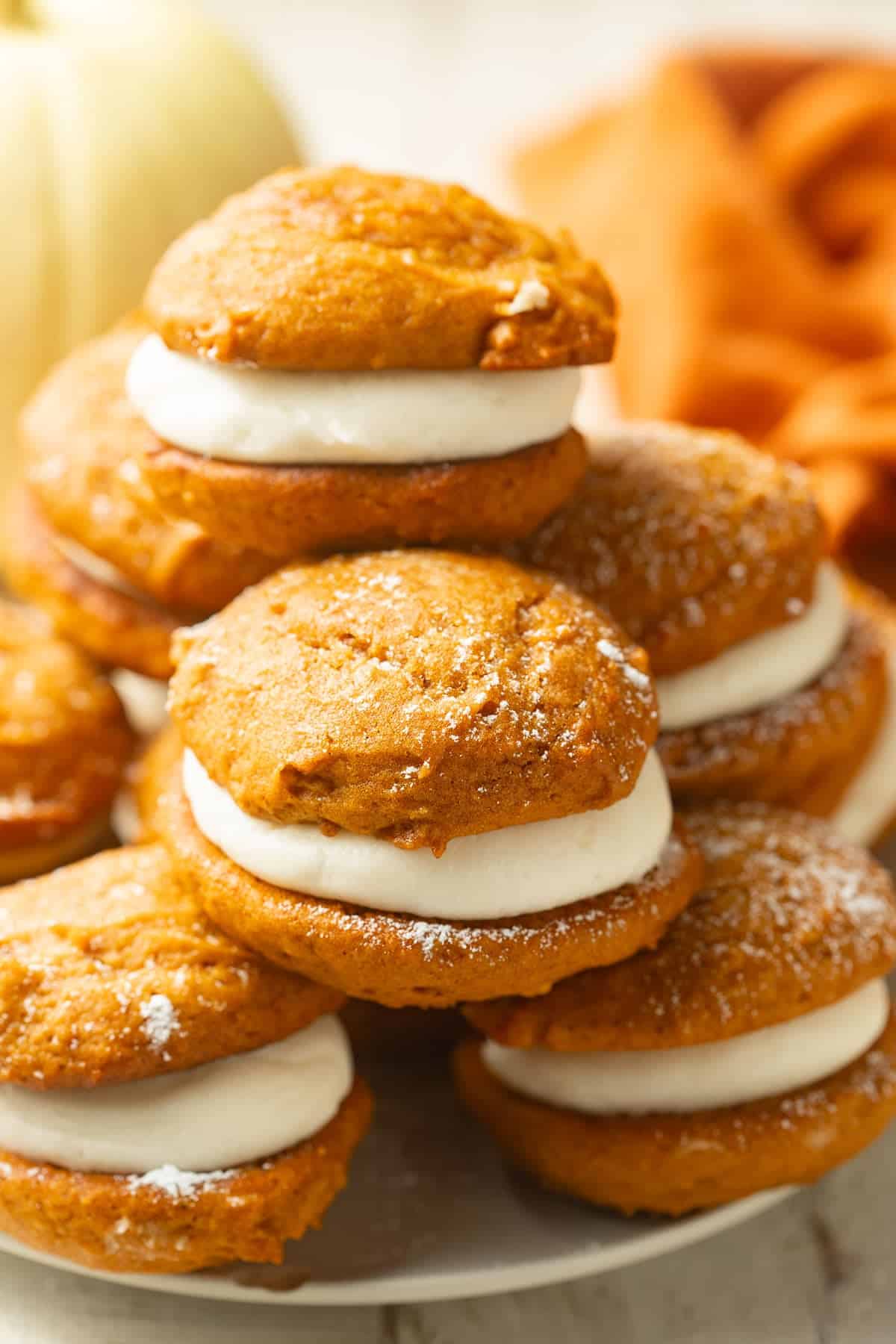 Plate of Vegan Pumpkin Whoopie Pies with pumpkin and napkin in background.
