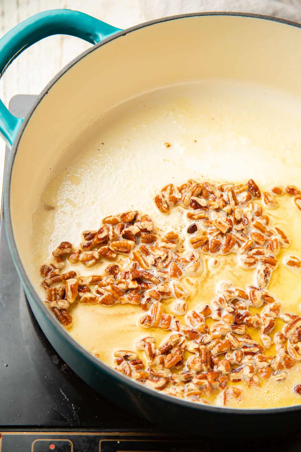 Chopped pecans in a pot with melted vegan butter.