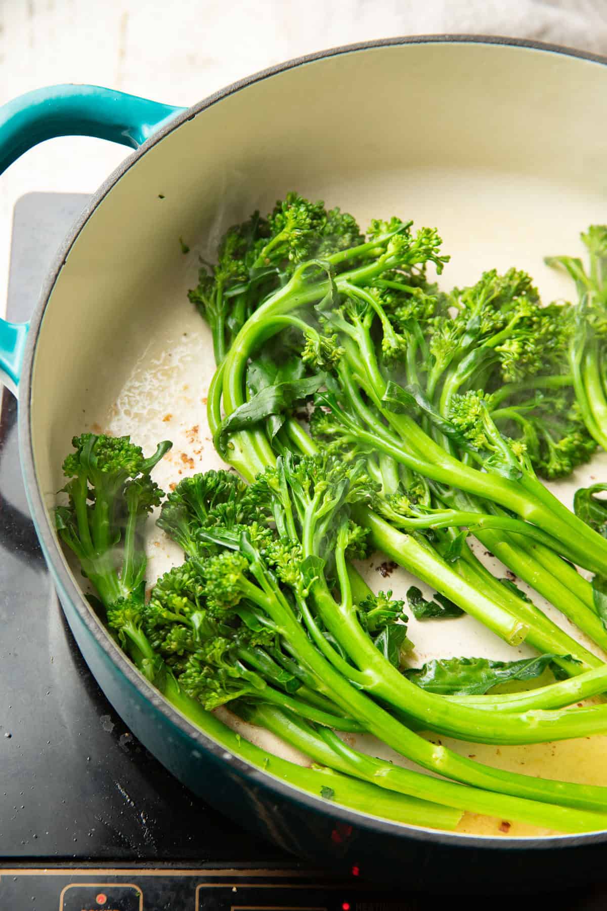 Broccolini stalks searing in a pot.