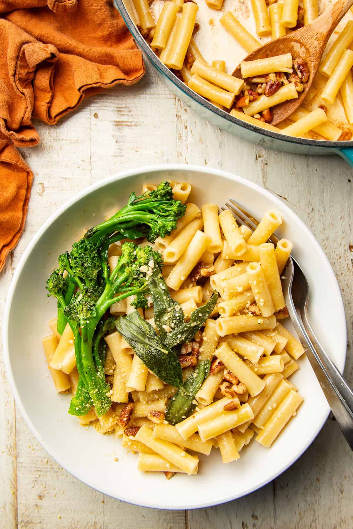 White wooden surface set with pot and bowl of Vegan Brown Butter Pasta.
