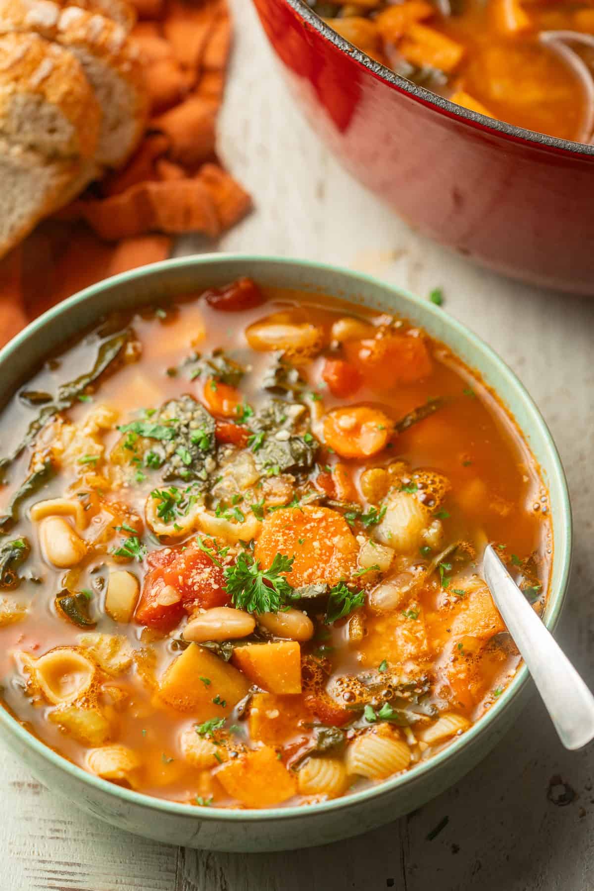 Bowl of Fall Minestrone with a pot and napkin in the background.