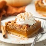 Pumpkin Pie Bar on a plate with whipped cream on top.