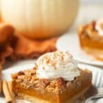 Pumpkin pie bar on a plate with a white pumpkin in the background.