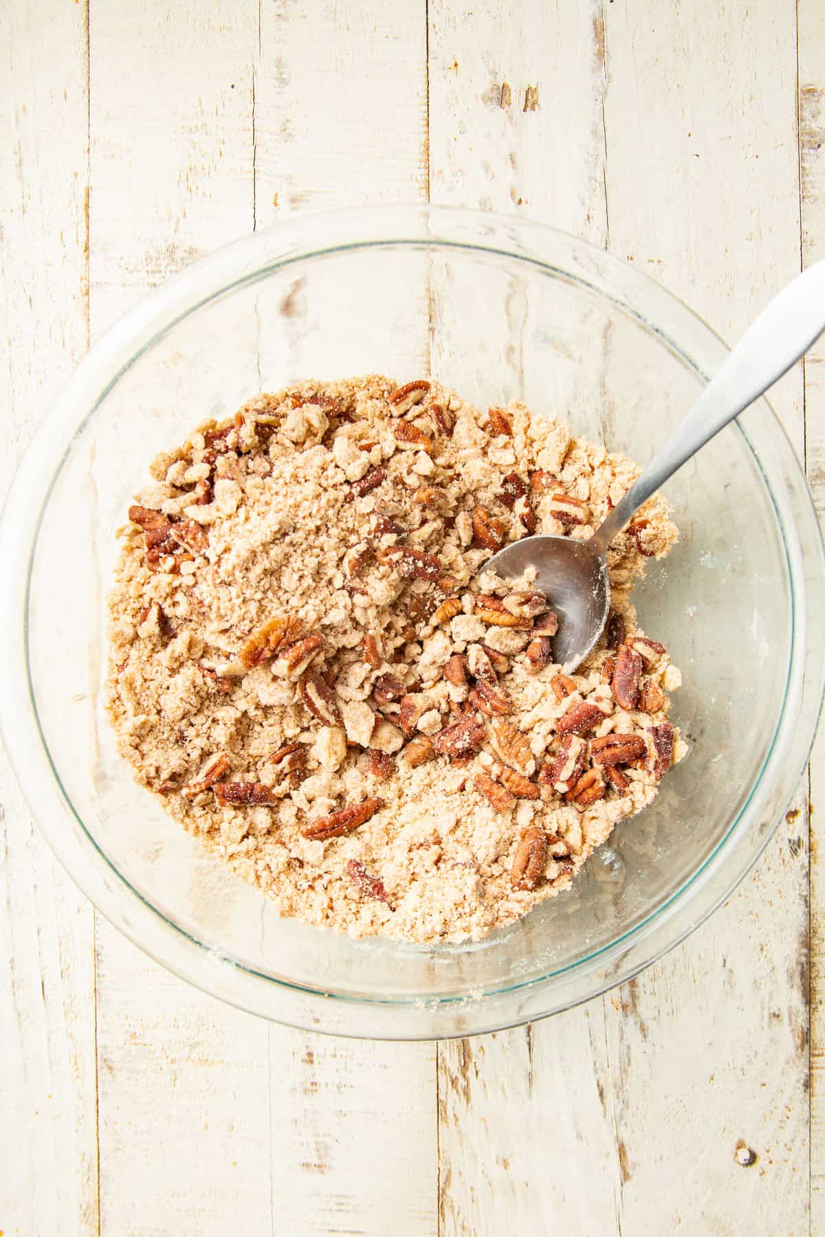 Pecan crumb topping in a mixing bowl with spoon.