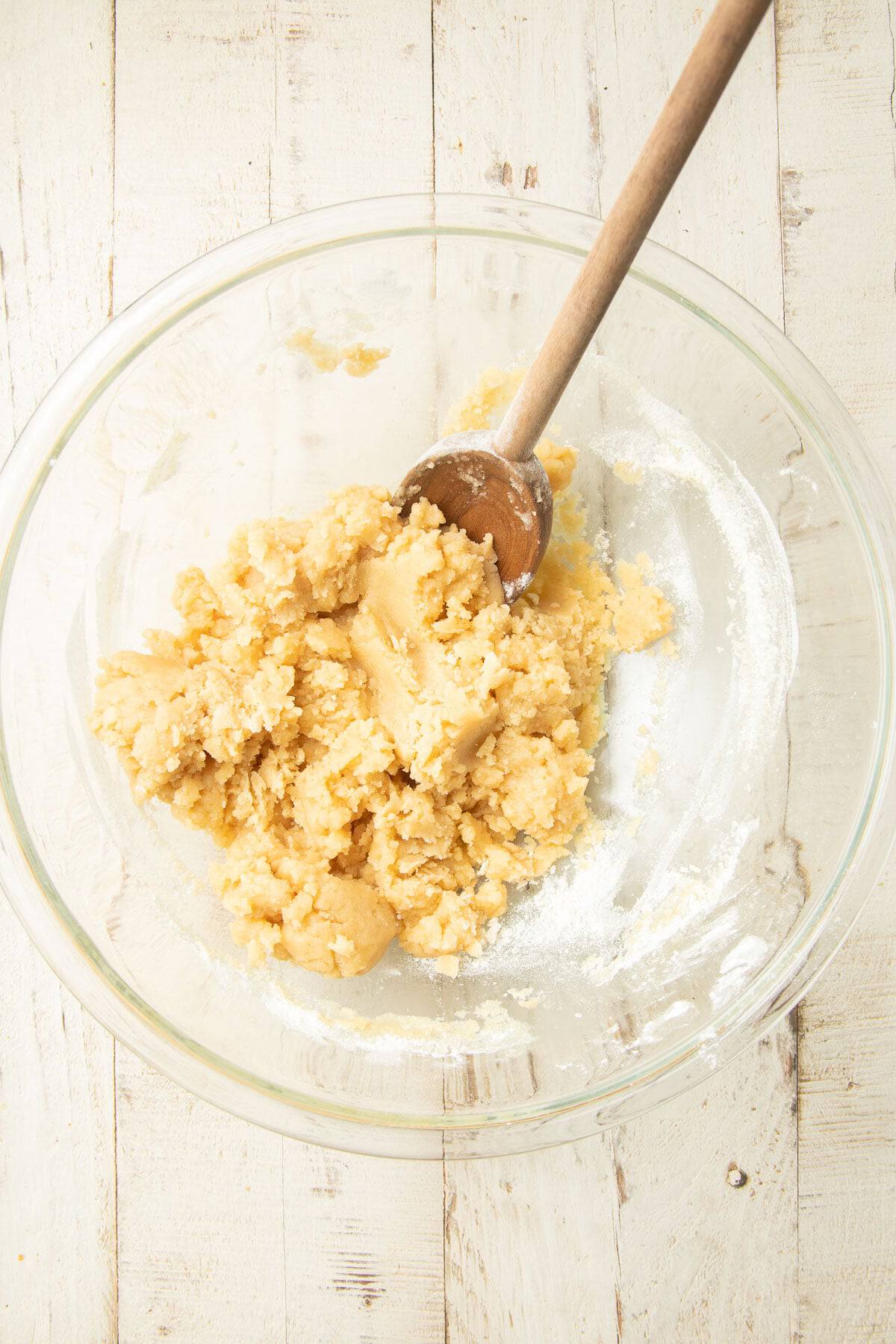 Dough for making Pumpkin Pie Bar crust in a mixing bowl with wooden spoon.