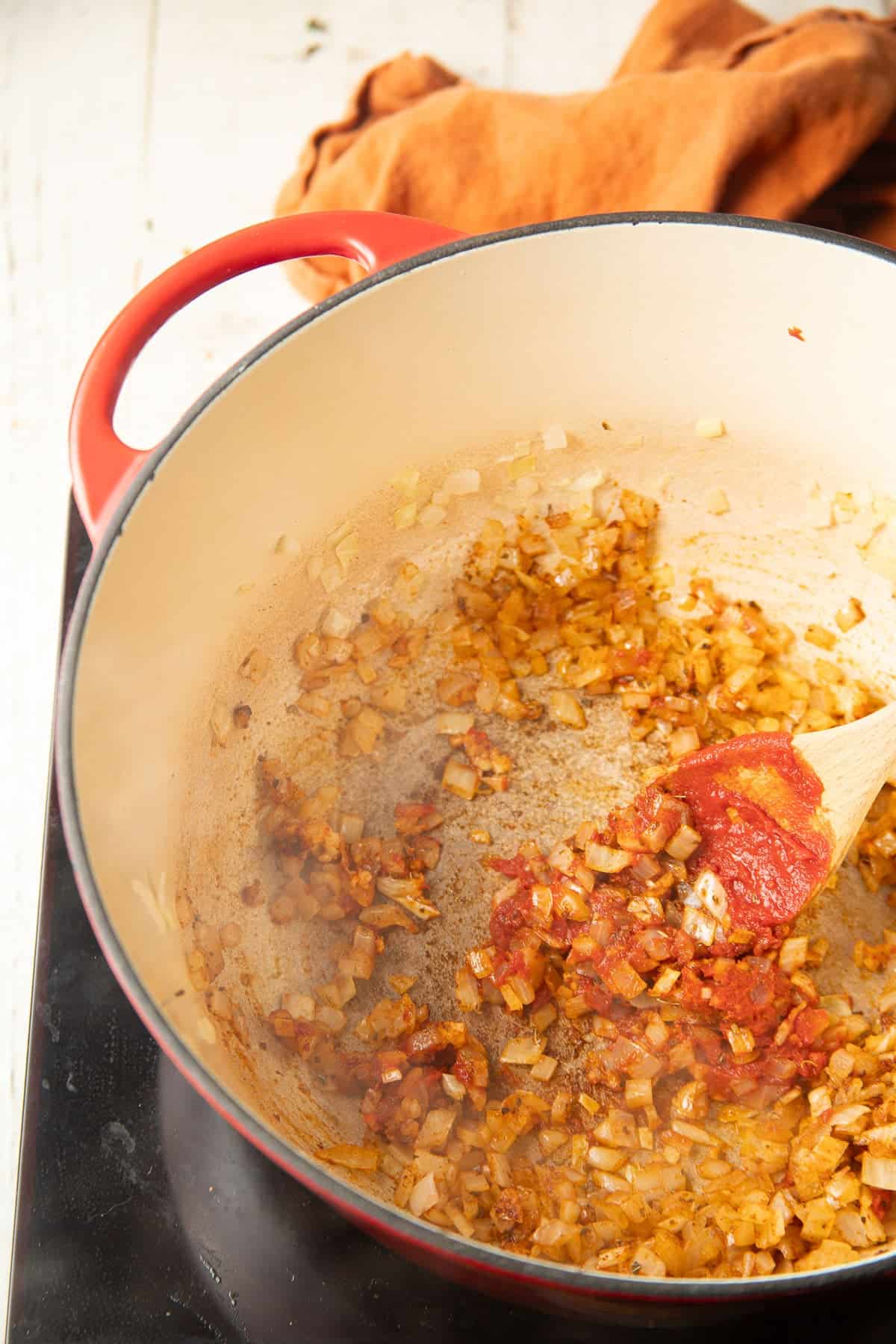 Garlic, onion, tomato paste, and spices cooking in a pot.