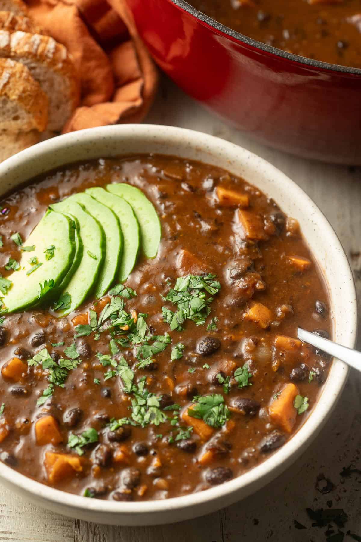 Bowl of Sweet Potato Black Bean Soup with a pot and bread in the background.
